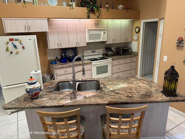 kitchen with stone counters, white appliances, sink, and light tile patterned floors