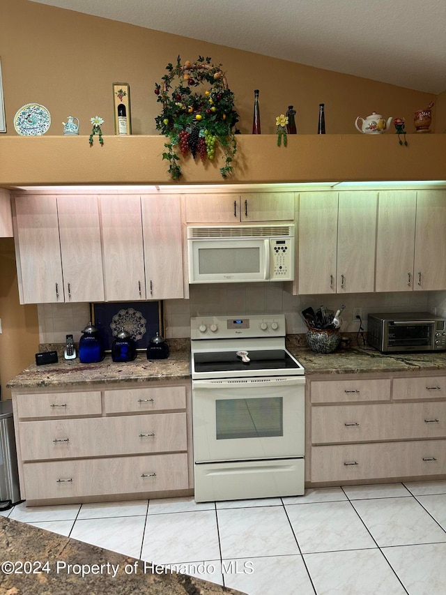 kitchen featuring light tile patterned flooring, white appliances, light brown cabinetry, and vaulted ceiling