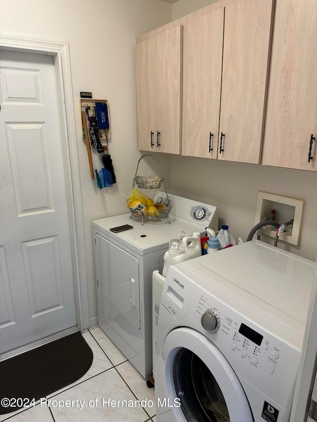 clothes washing area featuring cabinets, light tile patterned floors, and separate washer and dryer