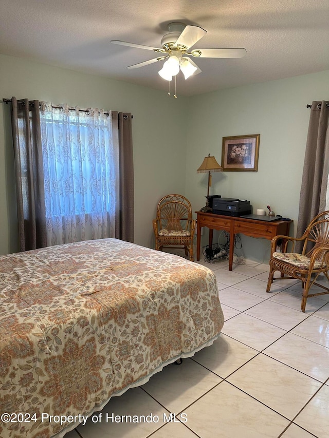 tiled bedroom with ceiling fan and a textured ceiling