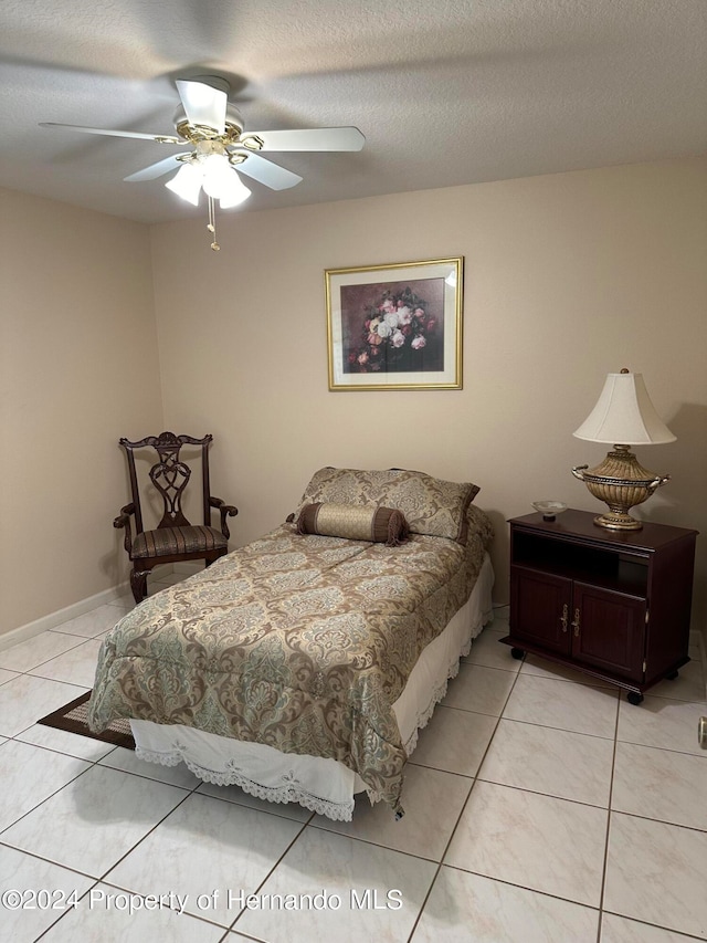 tiled bedroom featuring ceiling fan and a textured ceiling