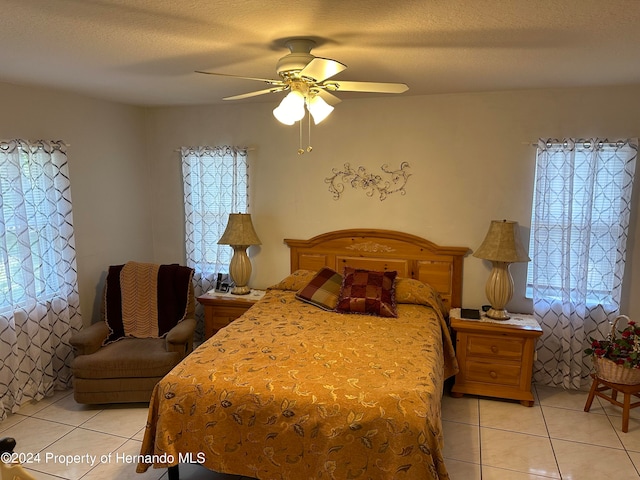 tiled bedroom featuring ceiling fan and a textured ceiling