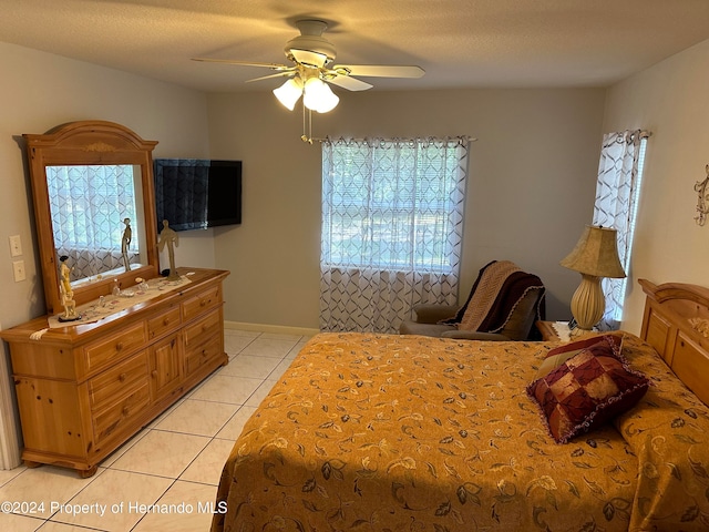 tiled bedroom with ceiling fan and a textured ceiling