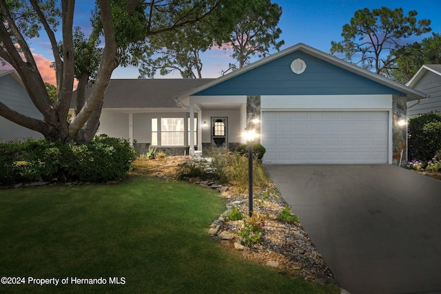 ranch-style home featuring a garage and a yard