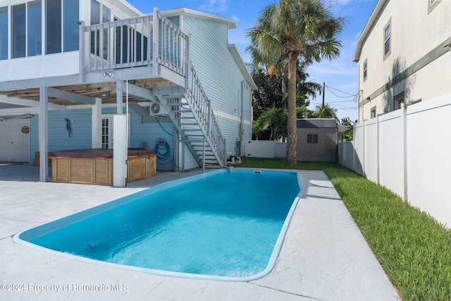 view of swimming pool featuring a shed, a hot tub, a patio area, and a sunroom