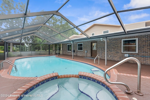 view of swimming pool with a pool with connected hot tub, glass enclosure, and a patio