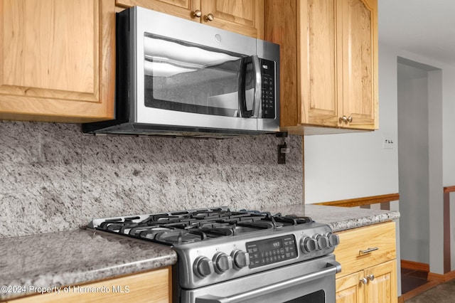 kitchen with stainless steel appliances, tasteful backsplash, and dark stone countertops