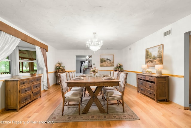 dining space with light wood finished floors, visible vents, and an inviting chandelier