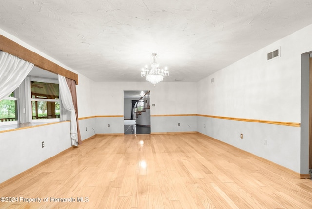 empty room featuring light hardwood / wood-style floors and an inviting chandelier