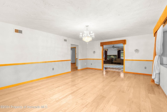 unfurnished living room featuring baseboards, light wood-style floors, visible vents, and a notable chandelier