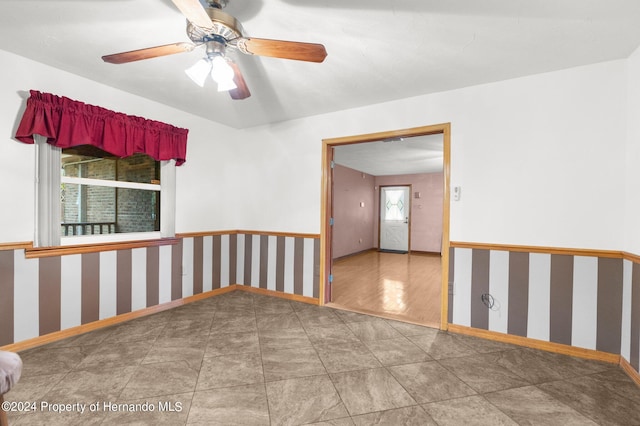 spare room featuring tile patterned floors, ceiling fan, baseboards, and wallpapered walls