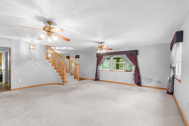 unfurnished living room with stairs, carpet floors, ceiling fan, and baseboards