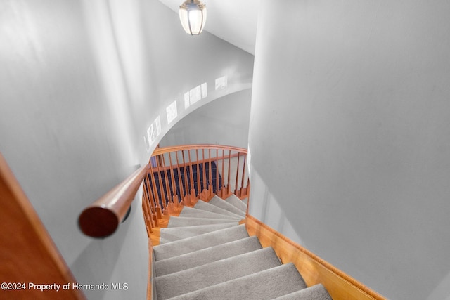 stairs featuring arched walkways and wood finished floors