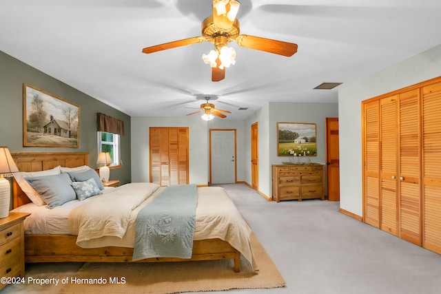 bedroom featuring two closets, light colored carpet, and ceiling fan