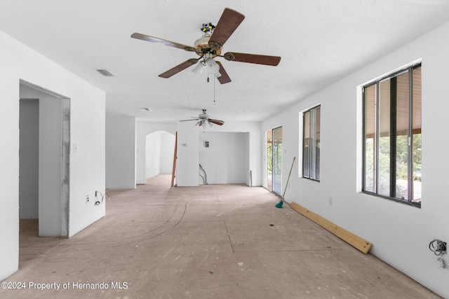 unfurnished living room with arched walkways and visible vents