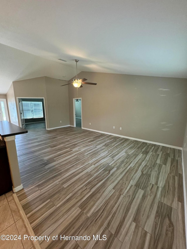 unfurnished living room with wood-type flooring, vaulted ceiling, and ceiling fan