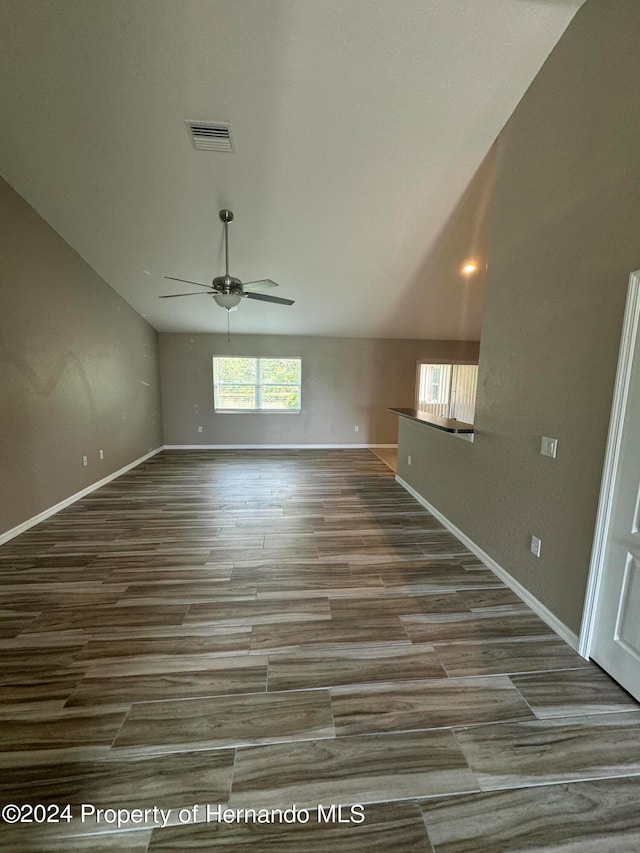 unfurnished living room with ceiling fan, wood-type flooring, and vaulted ceiling