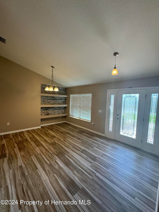 foyer with hardwood / wood-style floors, a notable chandelier, lofted ceiling, and a textured ceiling