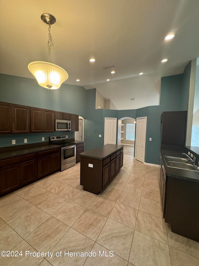 kitchen with sink, appliances with stainless steel finishes, decorative light fixtures, a kitchen island, and dark brown cabinets