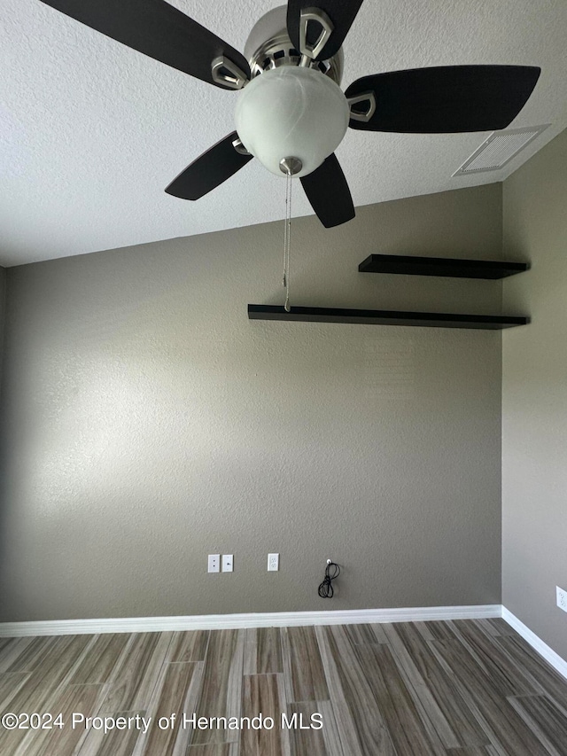 spare room featuring ceiling fan, wood-type flooring, a textured ceiling, and lofted ceiling