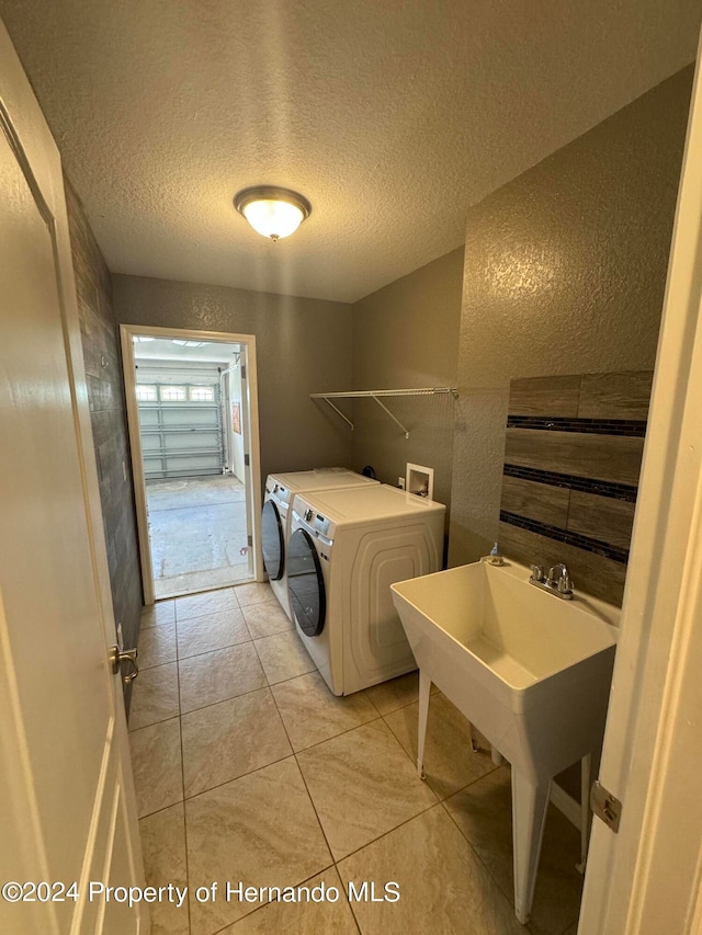 laundry room with washing machine and dryer, light tile patterned floors, and a textured ceiling