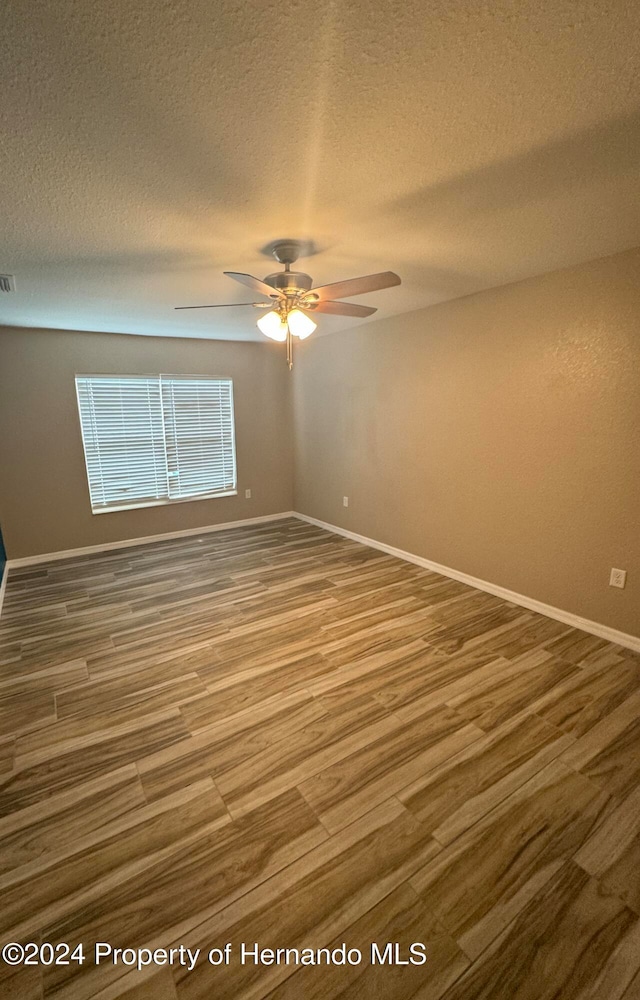 empty room with wood-type flooring, a textured ceiling, and ceiling fan