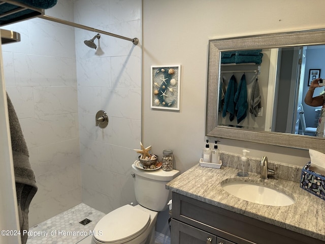 bathroom featuring toilet, vanity, and a tile shower