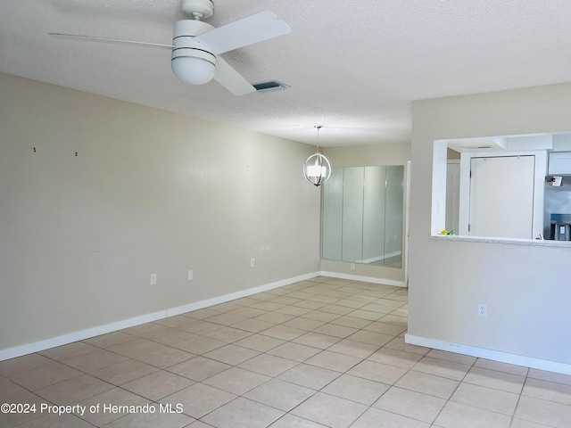 tiled empty room featuring a textured ceiling and ceiling fan