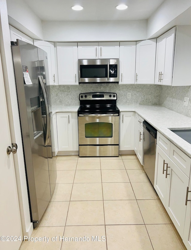 kitchen with white cabinets, stainless steel appliances, and light tile patterned flooring