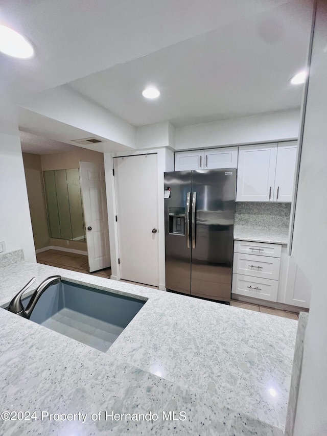 kitchen featuring fridge with ice dispenser, decorative backsplash, sink, and white cabinets