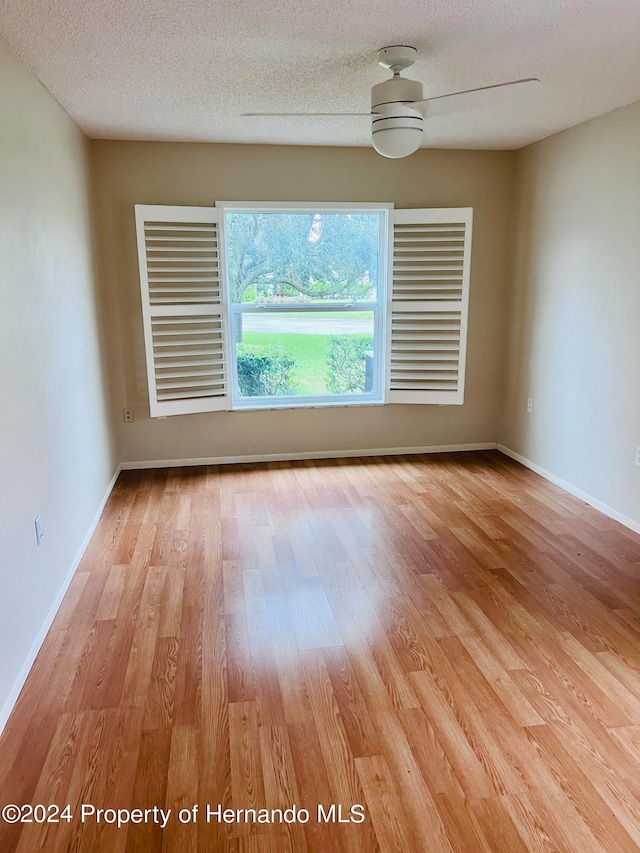 empty room with ceiling fan, a textured ceiling, and light hardwood / wood-style floors