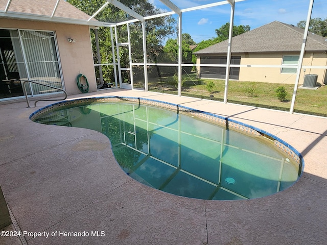 view of swimming pool with glass enclosure, cooling unit, and a patio area