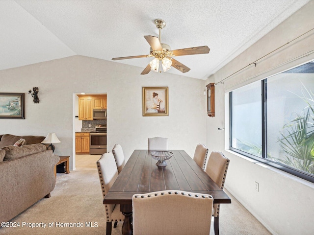 dining area featuring lofted ceiling, a textured ceiling, light colored carpet, and ceiling fan