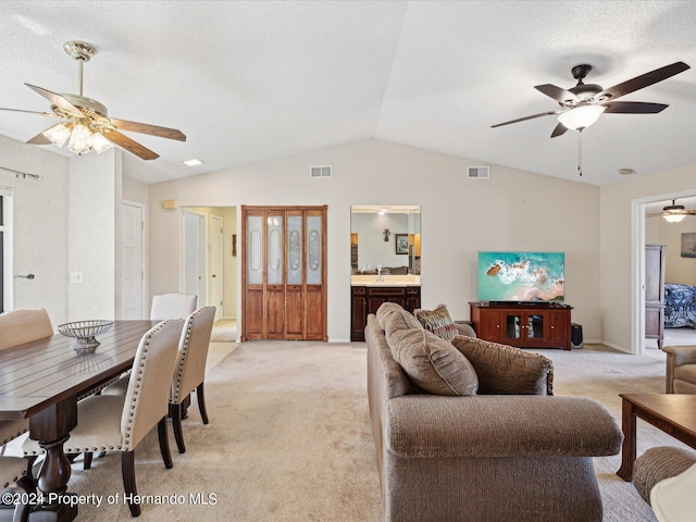 carpeted living room with a textured ceiling, ceiling fan, sink, and vaulted ceiling