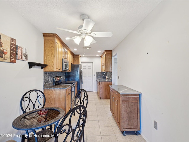 kitchen featuring stainless steel appliances, a textured ceiling, light tile patterned floors, and backsplash