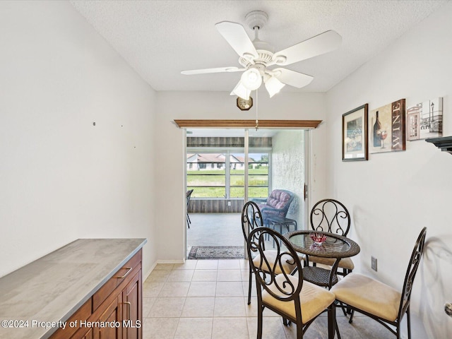 tiled dining area with ceiling fan and a textured ceiling