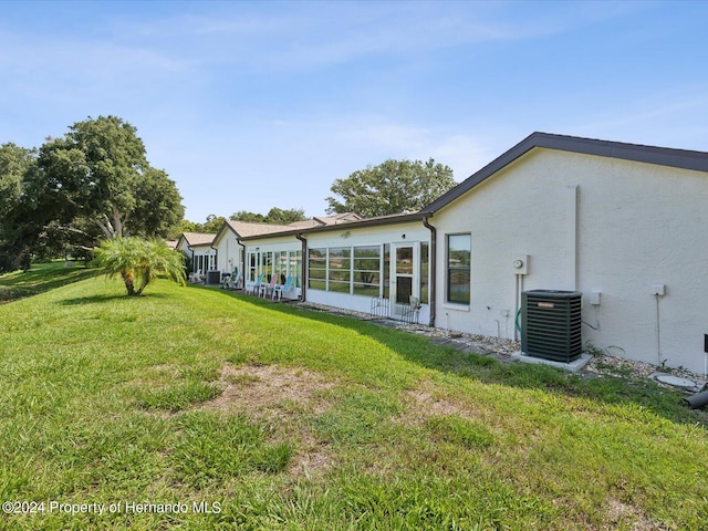 back of property featuring a lawn and central air condition unit