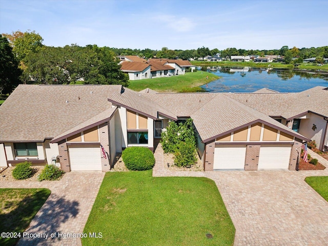 view of front of property with a garage, a water view, and a front yard