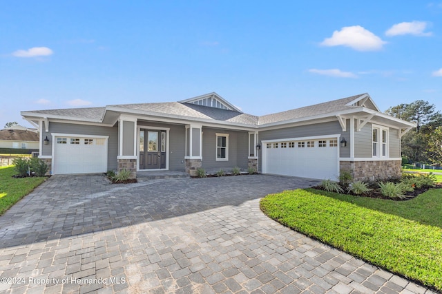 view of front of house featuring a front lawn, covered porch, and a garage