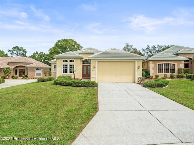 view of front of property with a garage, a front lawn, and french doors