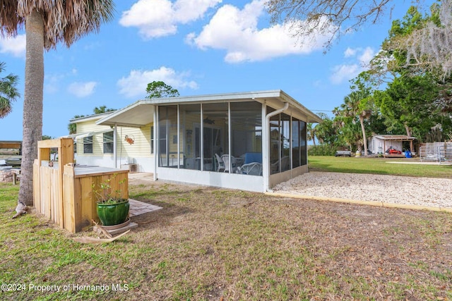 rear view of property featuring a sunroom and a yard