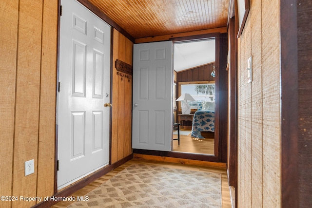 hallway featuring wood walls, lofted ceiling, wooden ceiling, and light hardwood / wood-style flooring