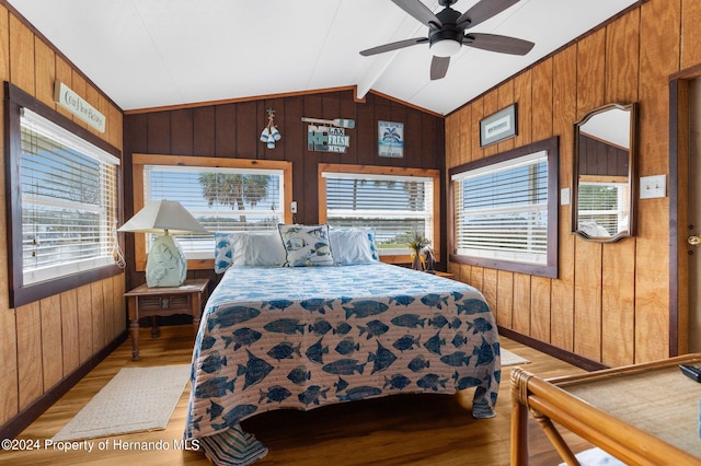 bedroom featuring wood walls, ceiling fan, and light hardwood / wood-style flooring