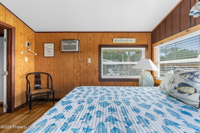 bedroom featuring wood walls, a wall unit AC, crown molding, and dark hardwood / wood-style flooring