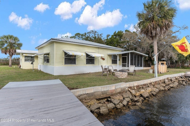 rear view of house featuring a yard, a sunroom, and an outdoor fire pit