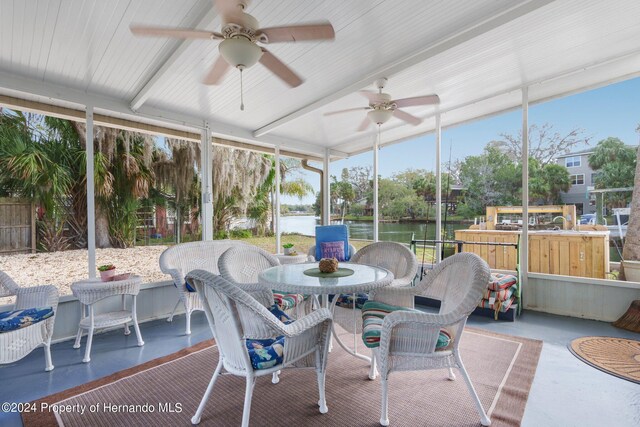 sunroom / solarium featuring a water view and ceiling fan