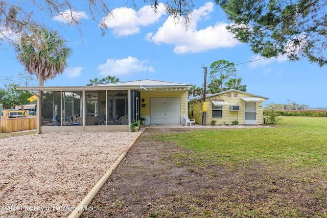 back of house with a sunroom, a yard, a wall unit AC, and a garage