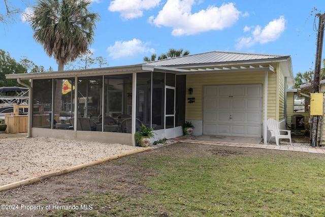 view of front facade featuring a garage, central AC, and a sunroom