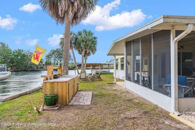 view of yard with a sunroom and a water view