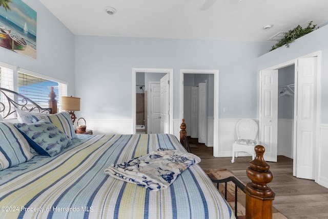 bedroom with a closet, a spacious closet, connected bathroom, dark wood-type flooring, and ceiling fan